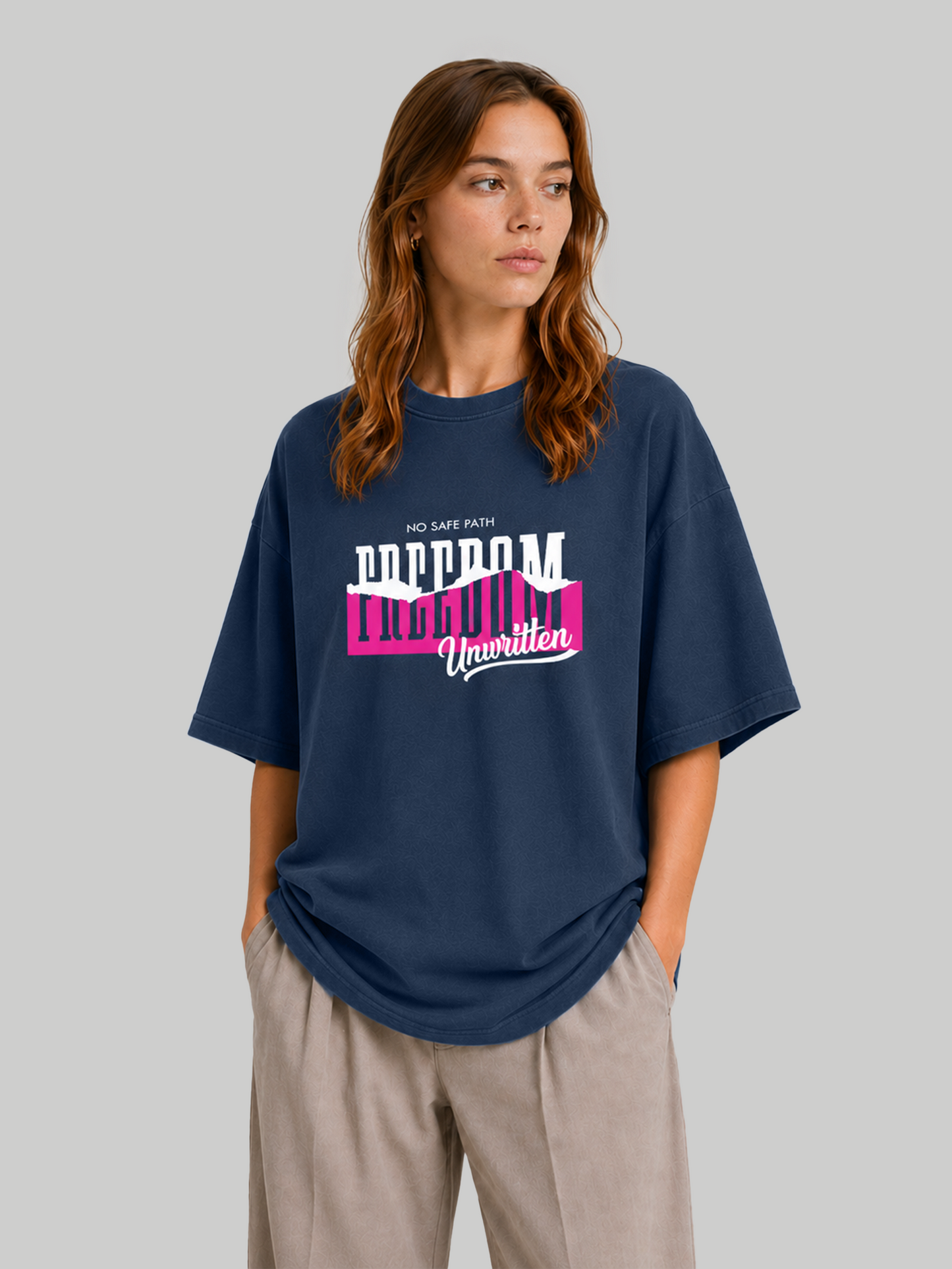 Women's oversized navy blue graphic tee featuring bold "Freedom Unwritten" design, angled front view with hands in pockets.