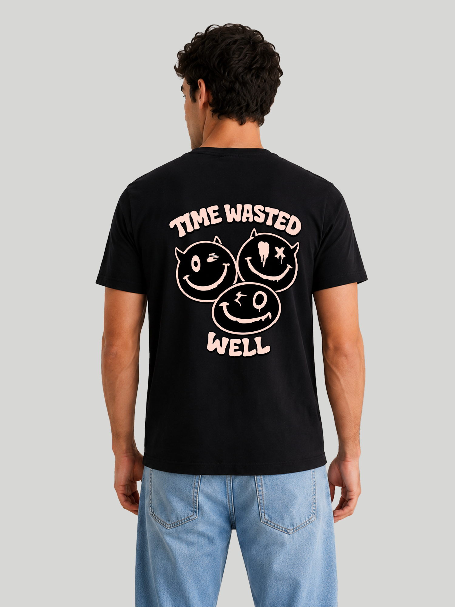 A straight back studio shot of a male model showcasing the regular fit of a black graphic streetwear t-shirt with a pink typography and smiley design.