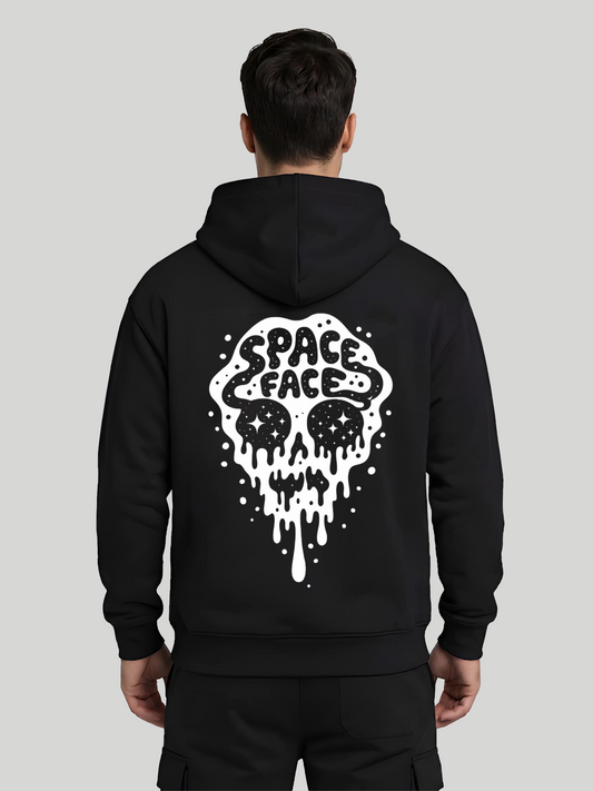 A straight rear studio view of a male model wearing a premium black pull-over hoodie featuring a large white surreal skull graphic with dripping accents and "SPACE FACE" typography printed on the back.