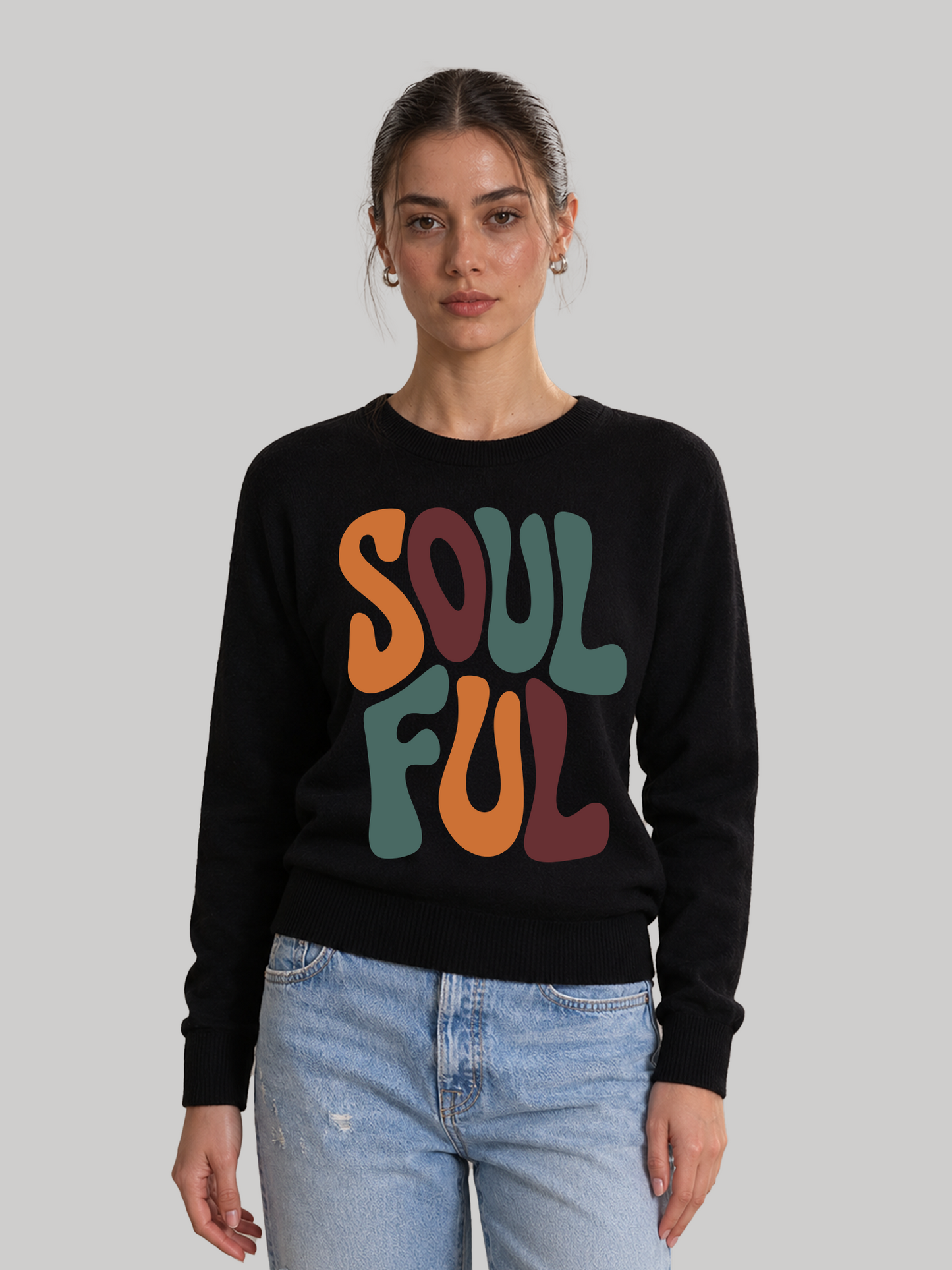 A full front view of a female model wearing a fitted black long-sleeve sweatshirt with a vibrant retro font design on the chest.