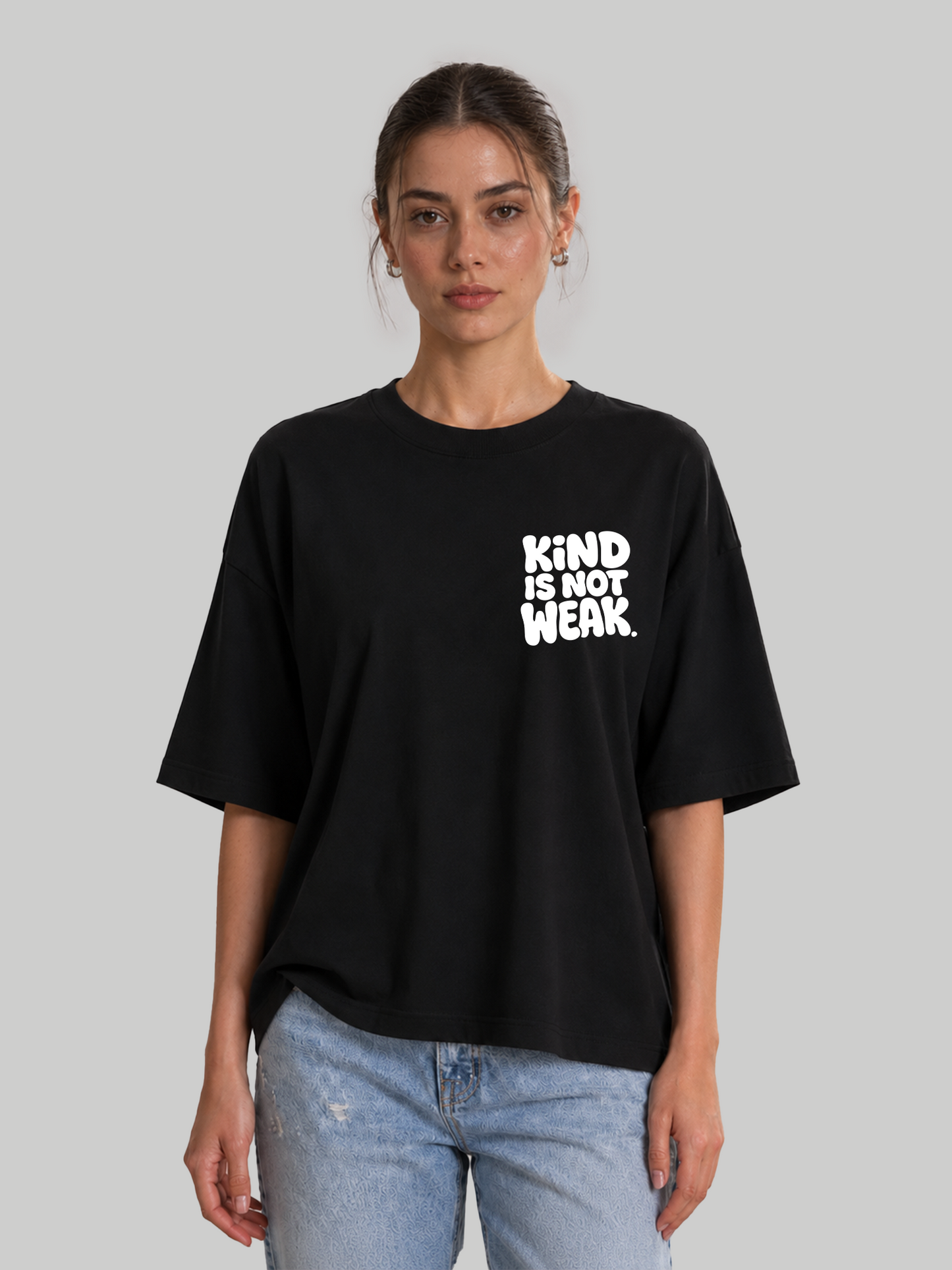 Women's oversized black relaxed-fit t-shirt featuring "Kind Is Not Weak" chest graphic, front view.