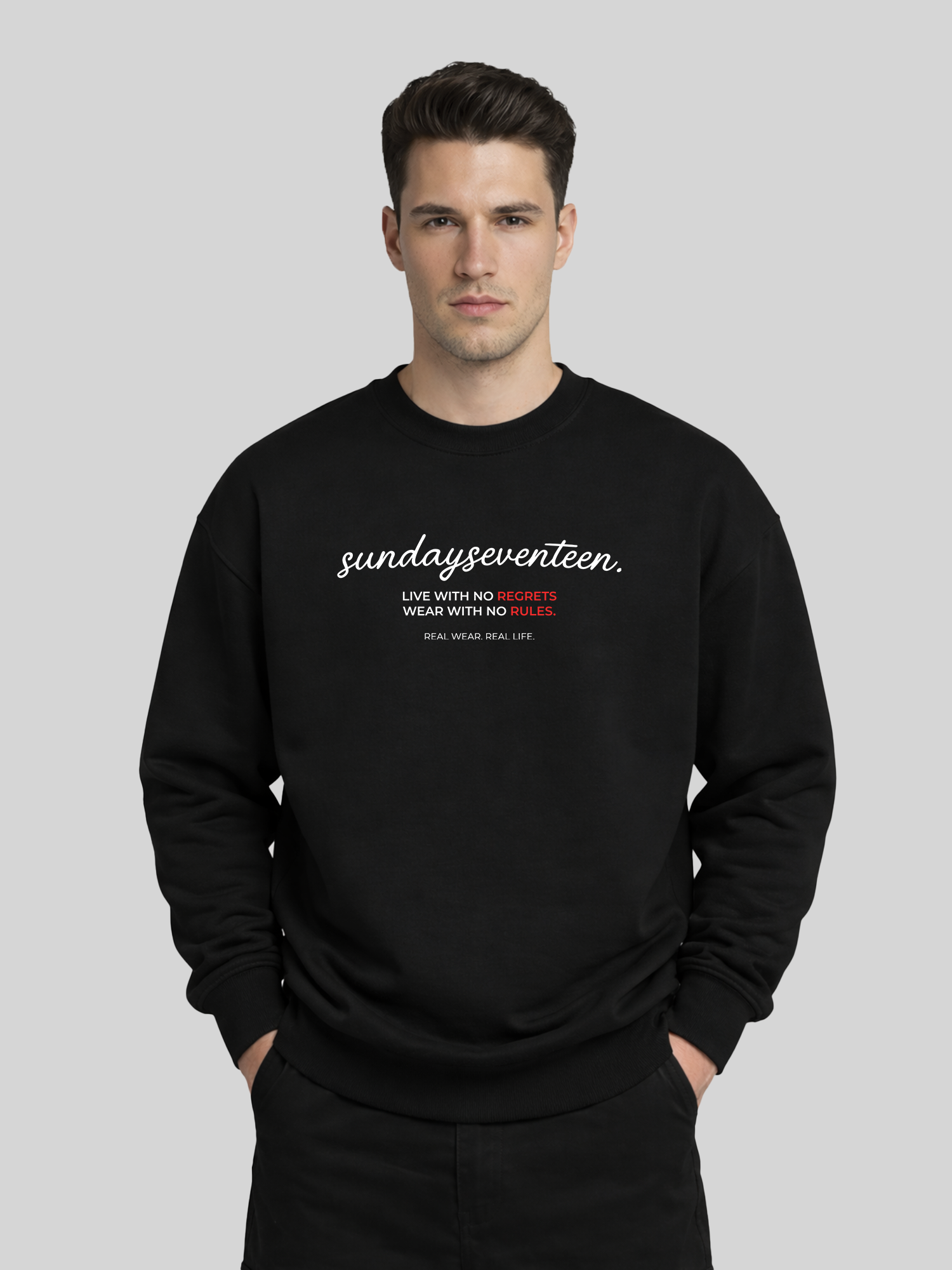 A front view of a male model wearing a black oversized sweatshirt with "sundayseventeen" printed in white cursive text and a red graphic message on the front.
