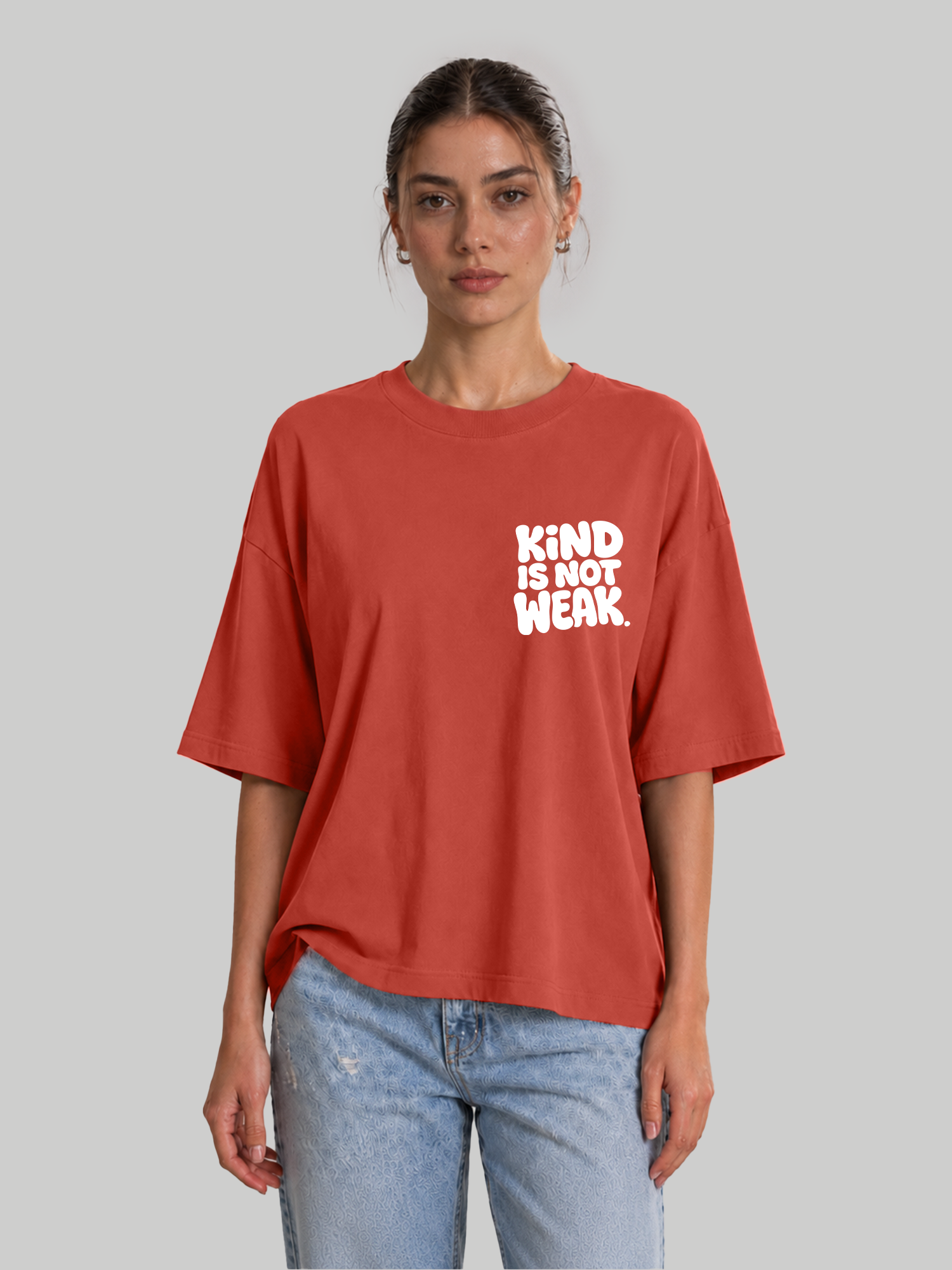 Women's oversized brick red t-shirt with "Kind Is Not Weak" chest print, front-facing view.