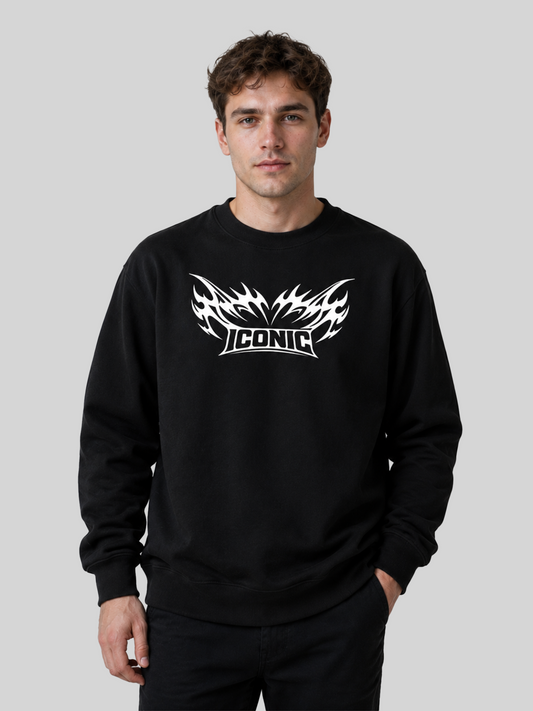 A front view of a male model wearing a black oversized sweatshirt with a white tribal flame graphic and "ICONIC" printed on the chest.