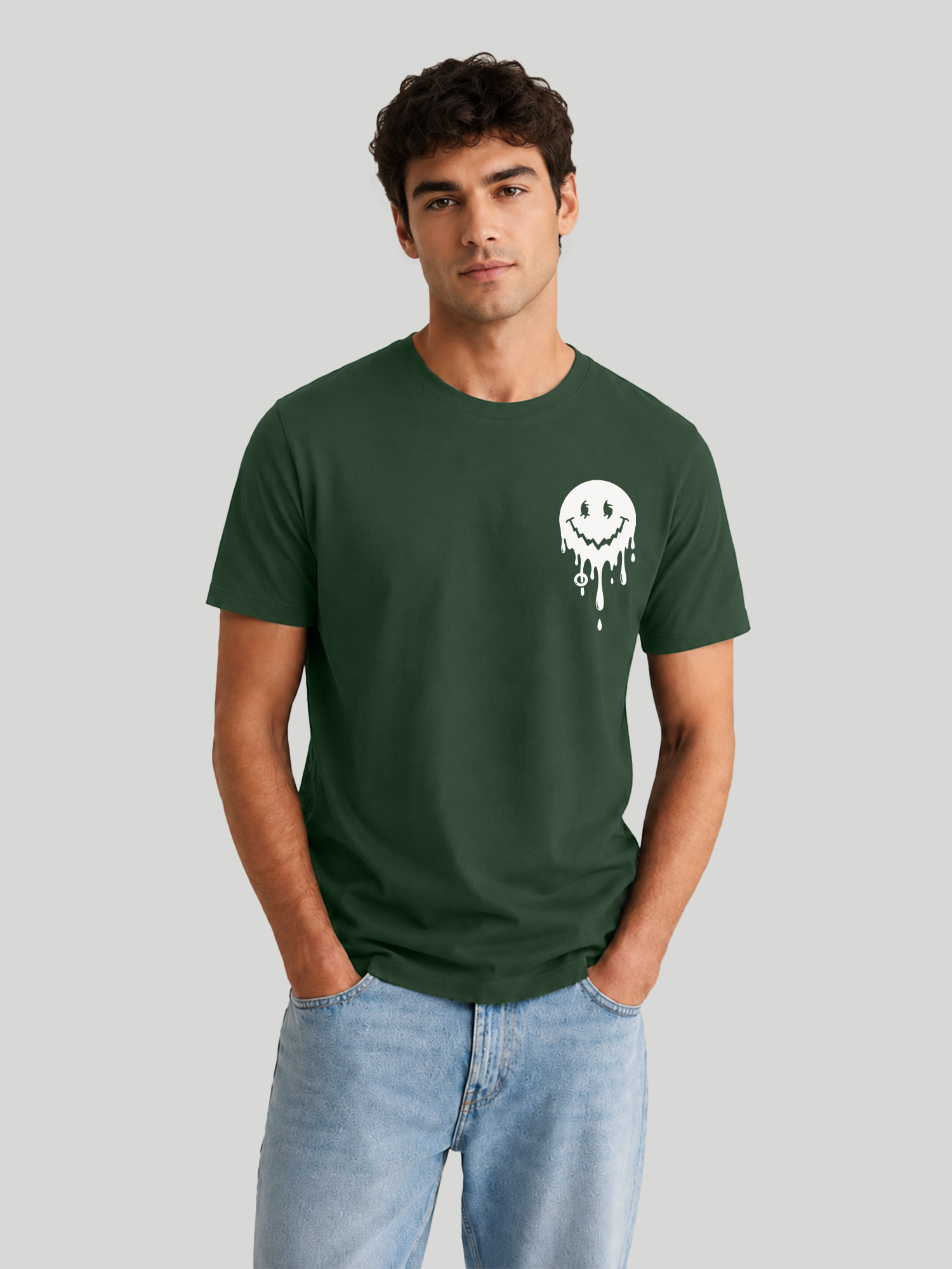 A front studio shot of a male model standing with both hands in his pockets, showcasing a casual olive green crew neck half-sleeve t-shirt.