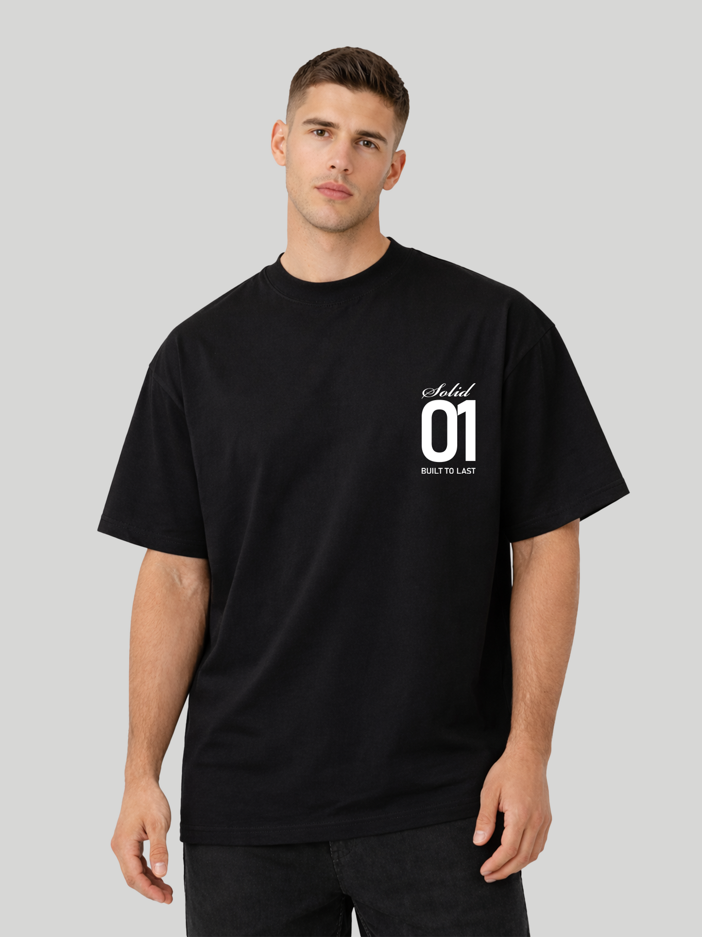 Man wearing black oversized t-shirt with Solid 01 chest print in relaxed tilted pose