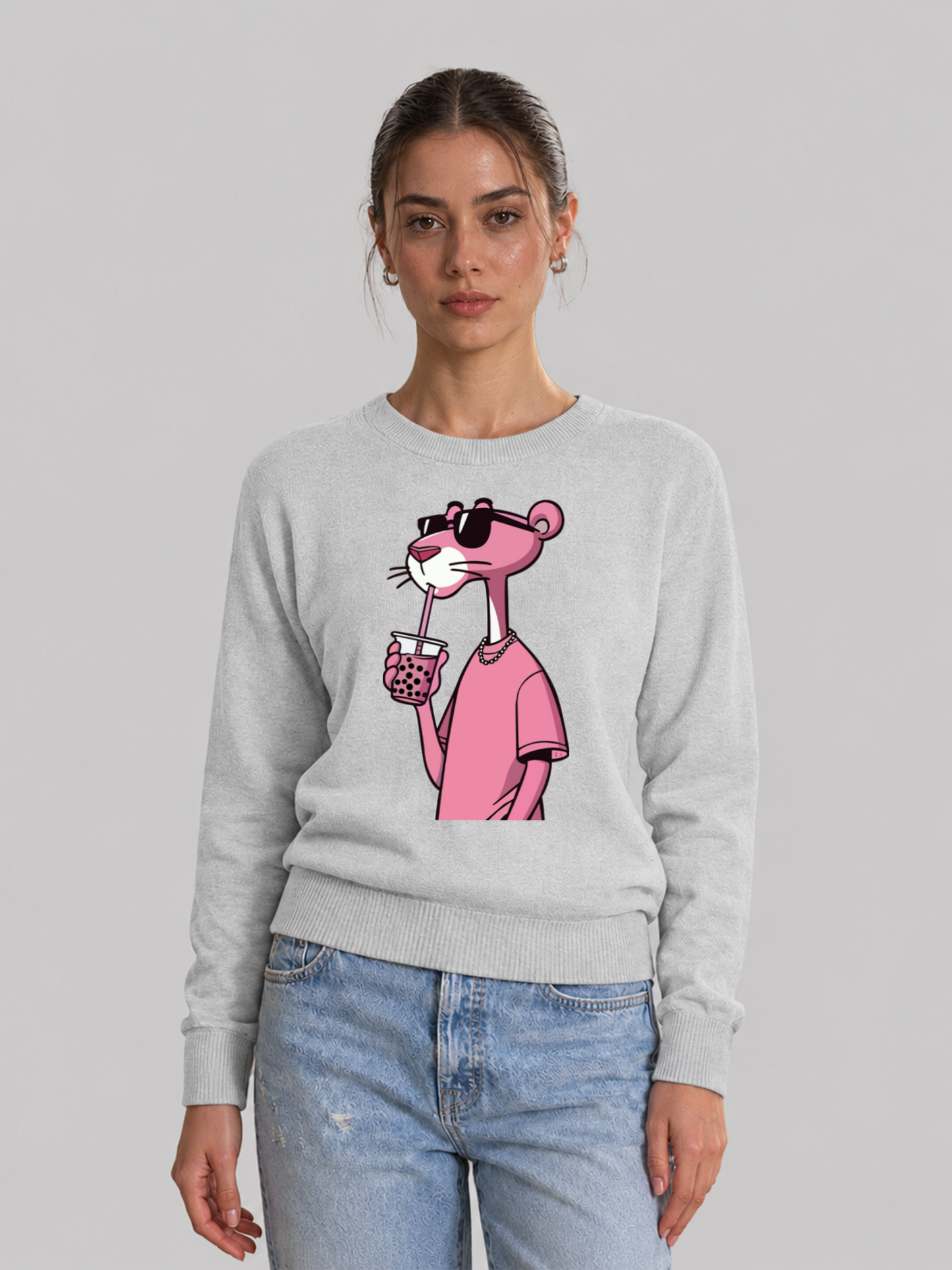 A full front view of a female model posing in an melange grey sweatshirt featuring a colorful graphic of the Pink Panther drinking bubble tea.