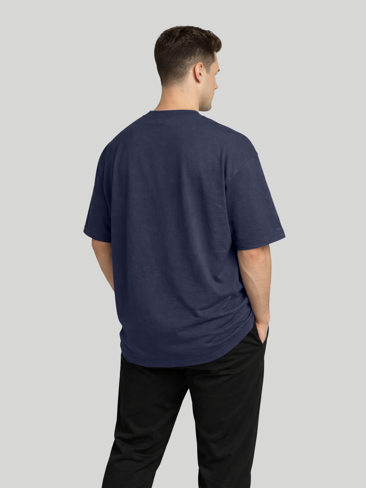 Back angled view of man wearing midnight blue oversized t-shirt with plain back design
