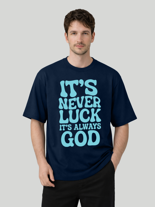 Man wearing navy blue oversized graphic t-shirt with It’s Never Luck It’s Always God front print in angled standing pose