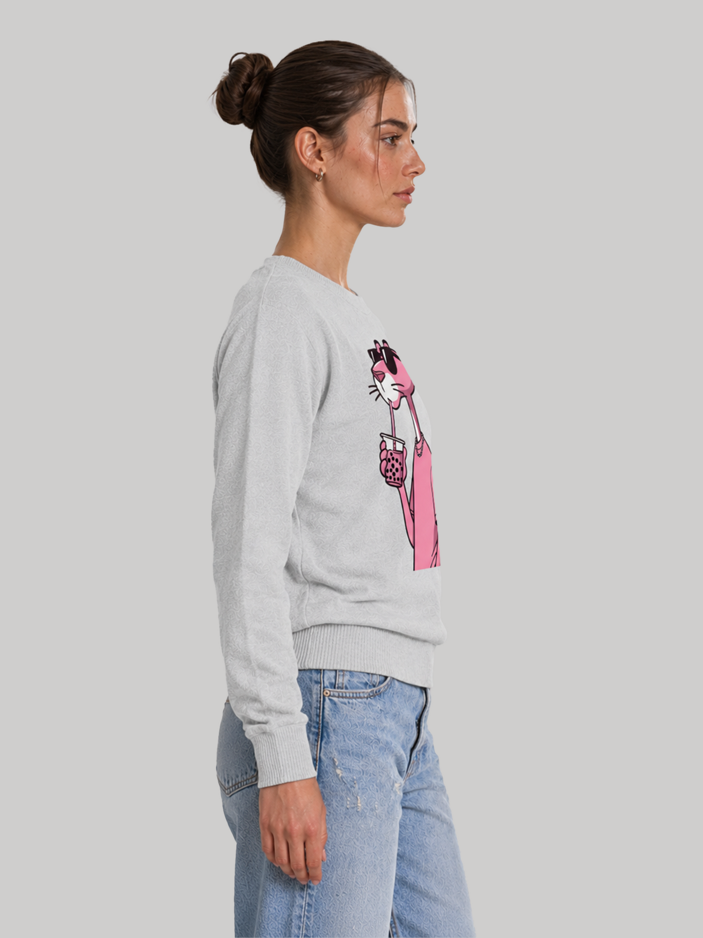 A side profile view of a female model wearing an melange grey crewneck graphic sweatshirt, showcasing the sleeve cuffs and relaxed fit.