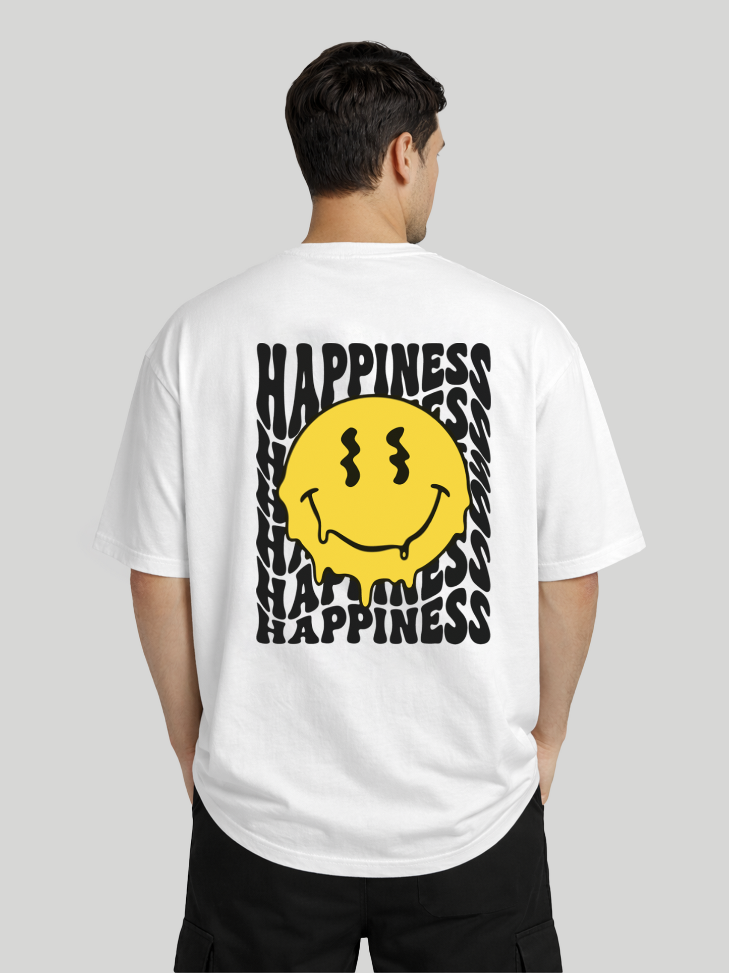 Back angled view of man wearing white oversized t-shirt with Happiness back graphic and yellow dripping smiley print