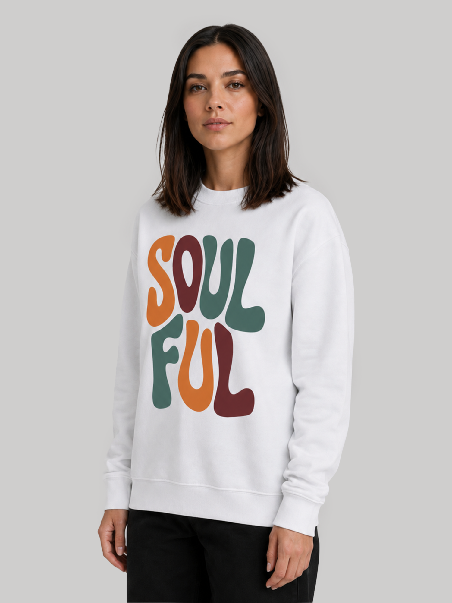 A slight three-quarter view of a female model posing in a white long-sleeve graphic sweatshirt, showing the sleeve length and neckline fit.