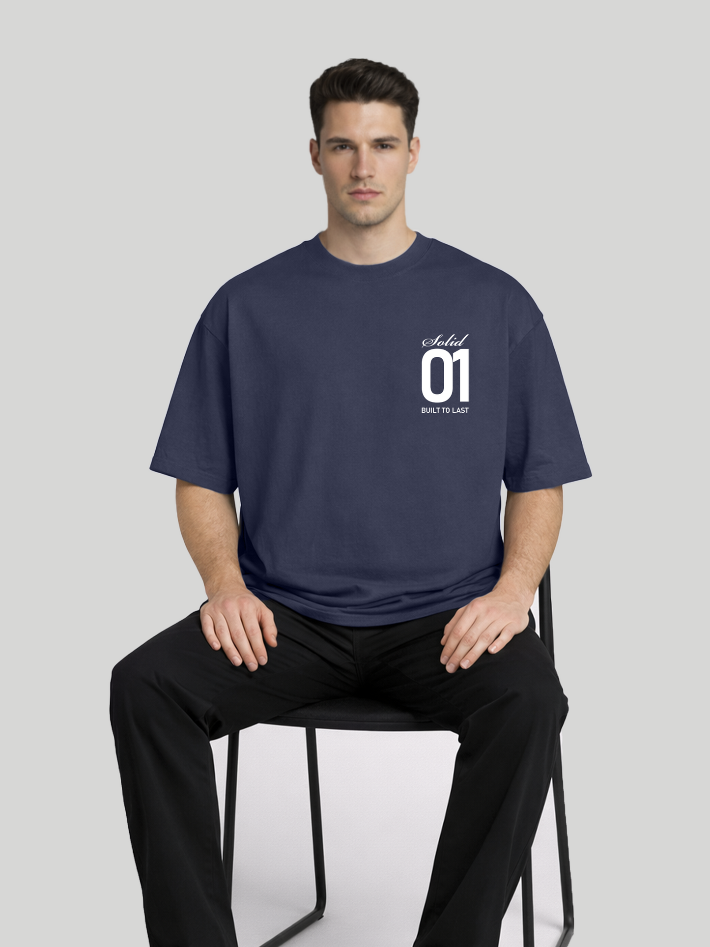 Man sitting on chair wearing midnight blue oversized t-shirt with Solid 01 chest print