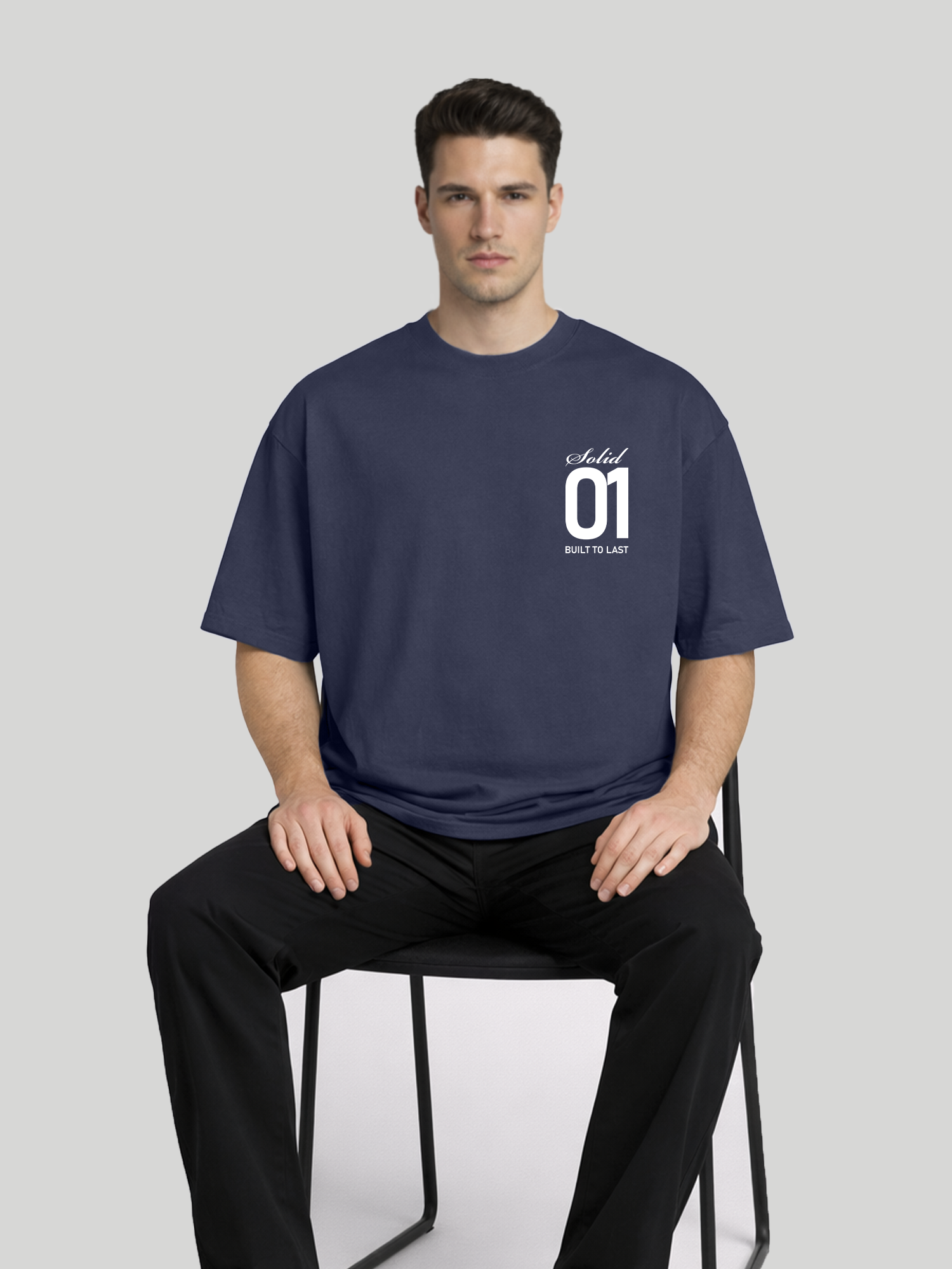 Man sitting on chair wearing midnight blue oversized t-shirt with Solid 01 chest print