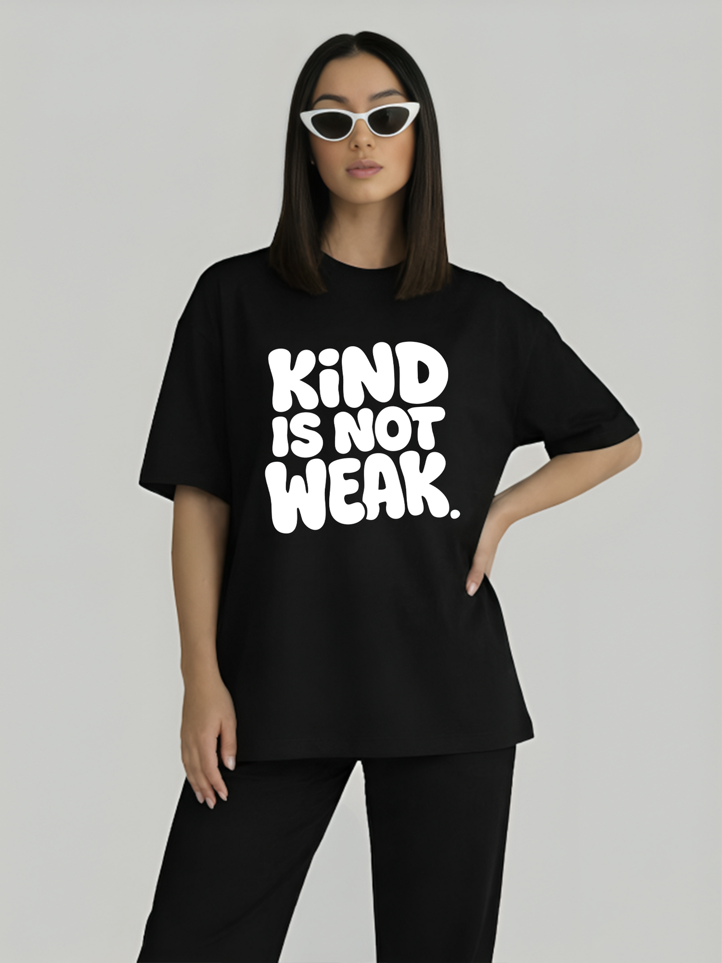 Model wearing black oversized slogan t-shirt for women with Kind Is Not Weak design