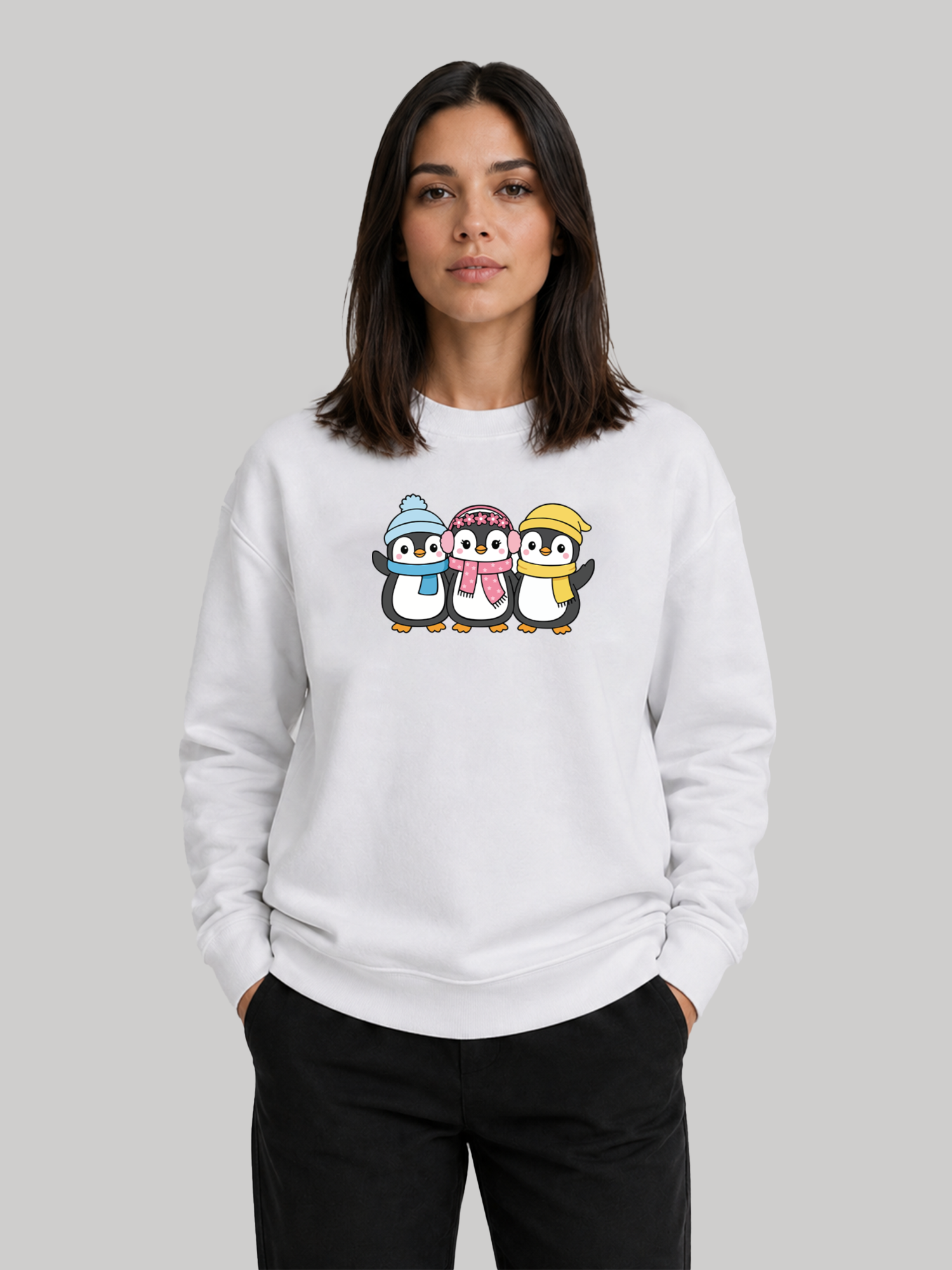 A front view of a female model standing with her hands in her pockets, wearing a white custom printed sweatshirt featuring a cute penguin design.