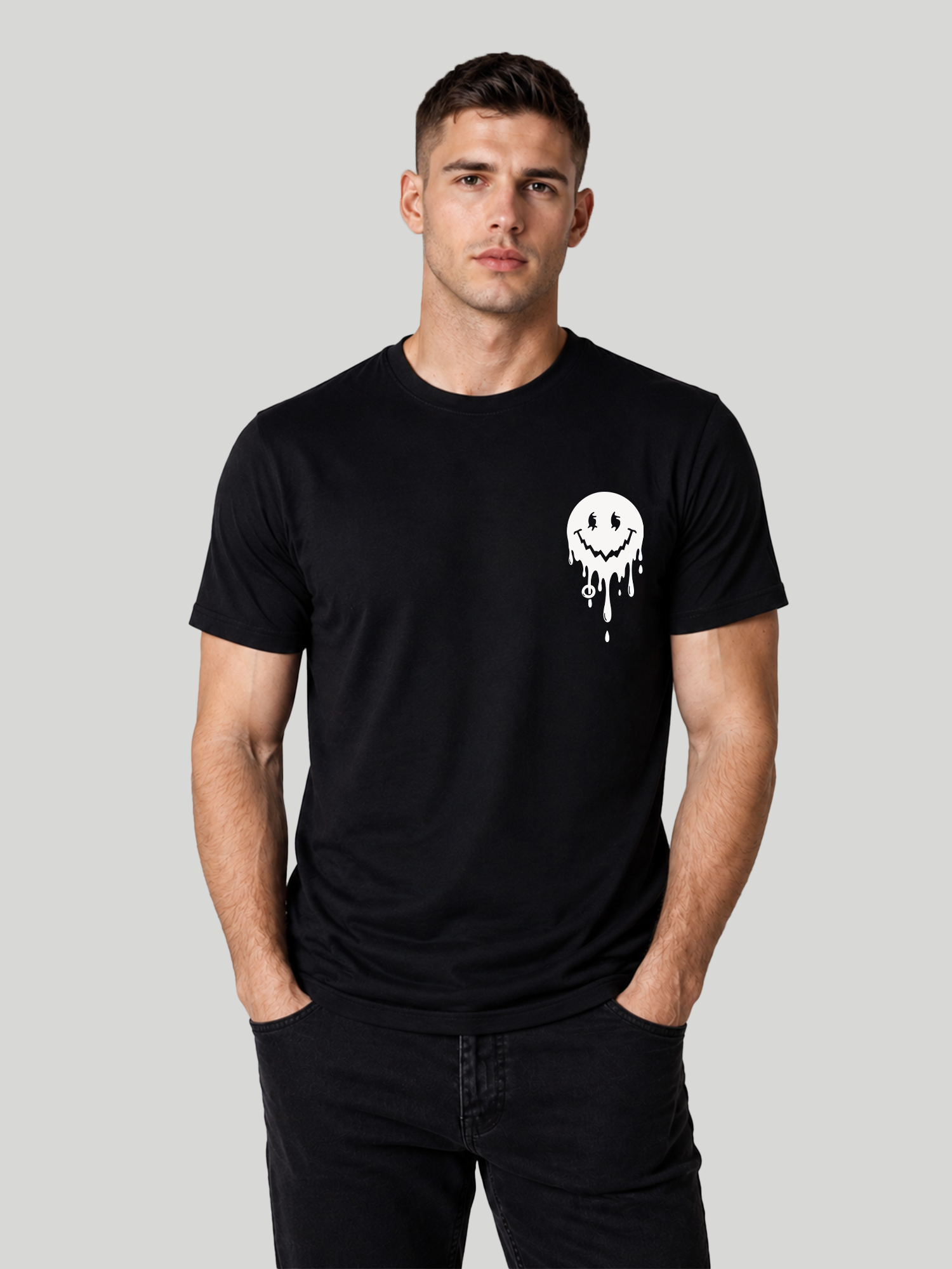 A front view of a male model standing with both hands in his pockets, showcasing the casual fit of a black crew neck cotton t-shirt with a dripping smiley chest design.