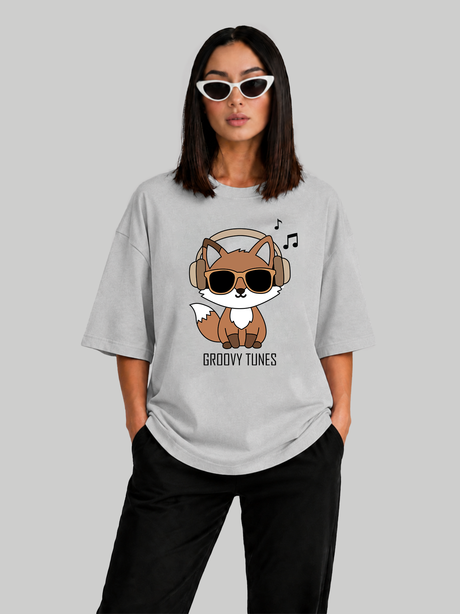 Women's oversized ash grey graphic tee with Groovy Tunes fox design, front-facing pose with hands in pockets.