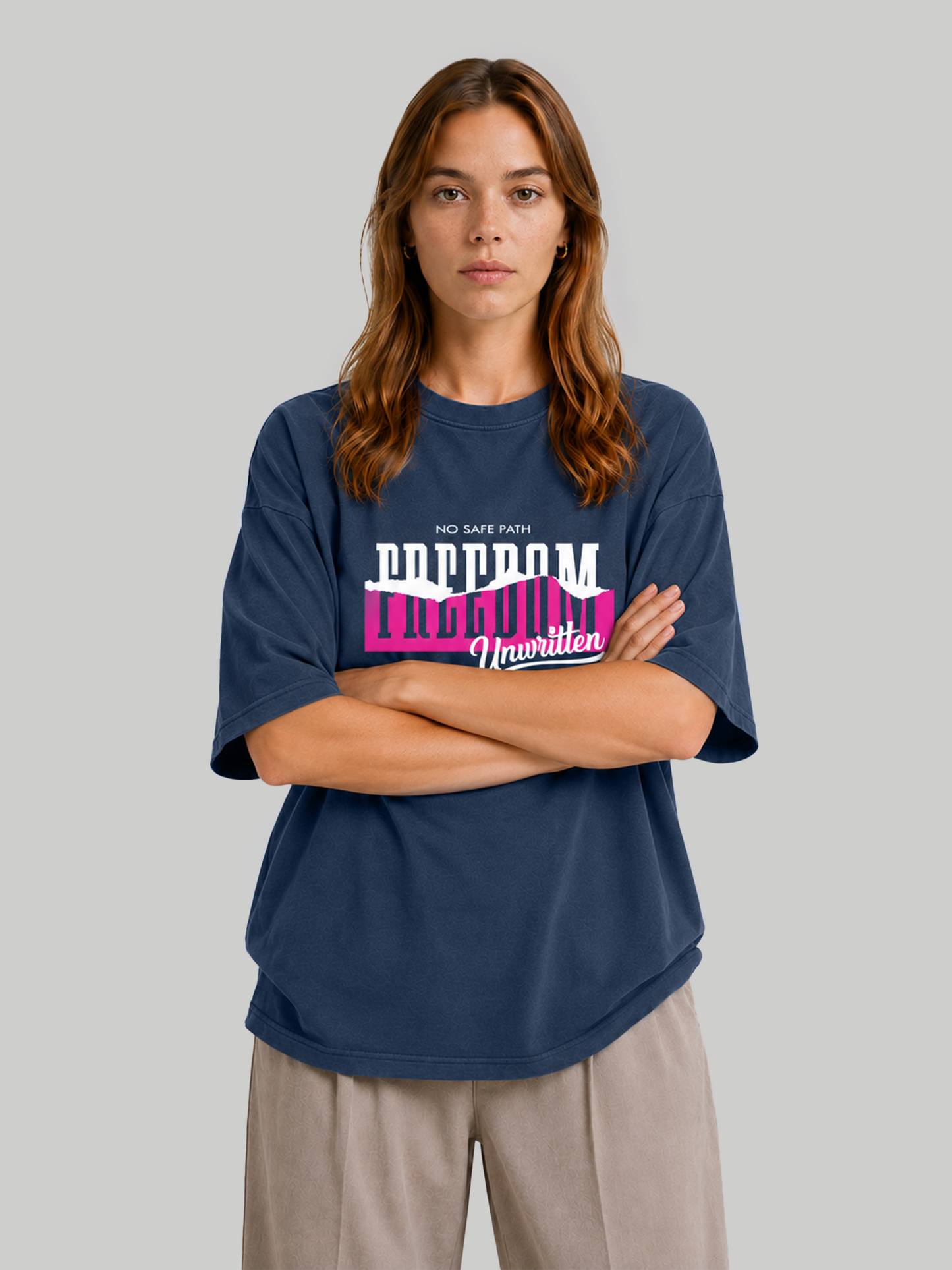 Women's oversized navy blue t-shirt with "Freedom Unwritten" typography print, front-facing pose with arms crossed.
