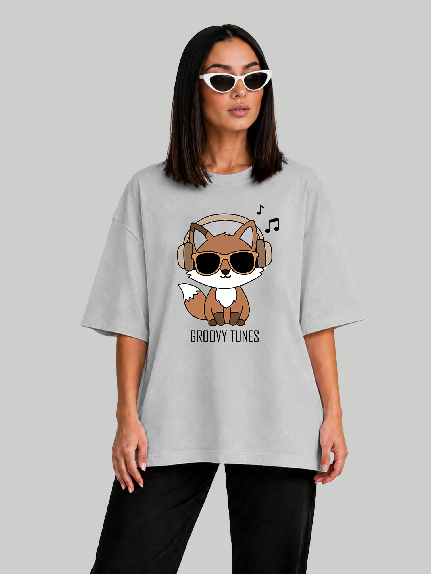 Women's oversized ash grey t-shirt featuring a Groovy Tunes fox graphic with headphones and sunglasses, angled front view.