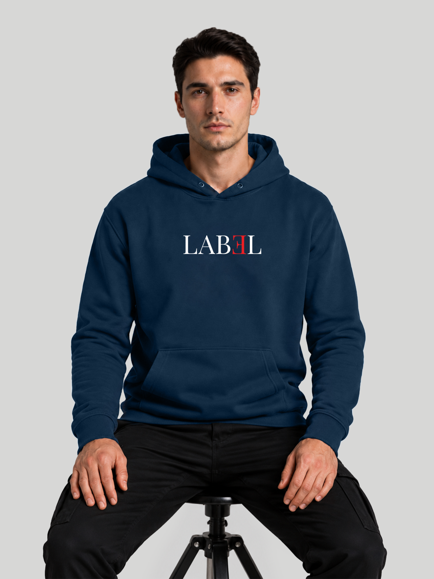 Men's LABEL navy blue graphic hoodie in seated pose with premium streetwear styling