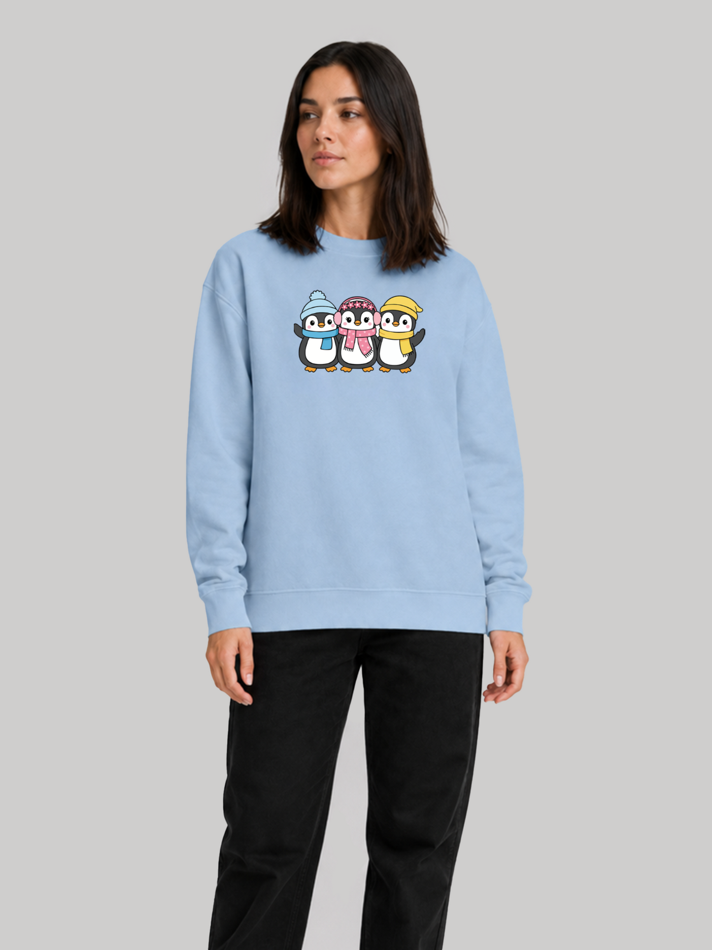 A three-quarter view of a female model looking to the side, wearing a relaxed-fit baby blue graphic sweatshirt paired with black pants.