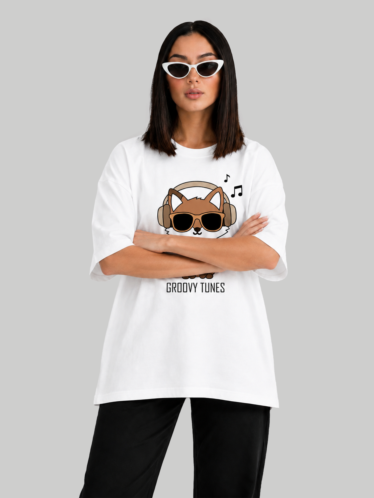 Women's oversized white graphic tee with Groovy Tunes fox design, front-facing pose with arms crossed.