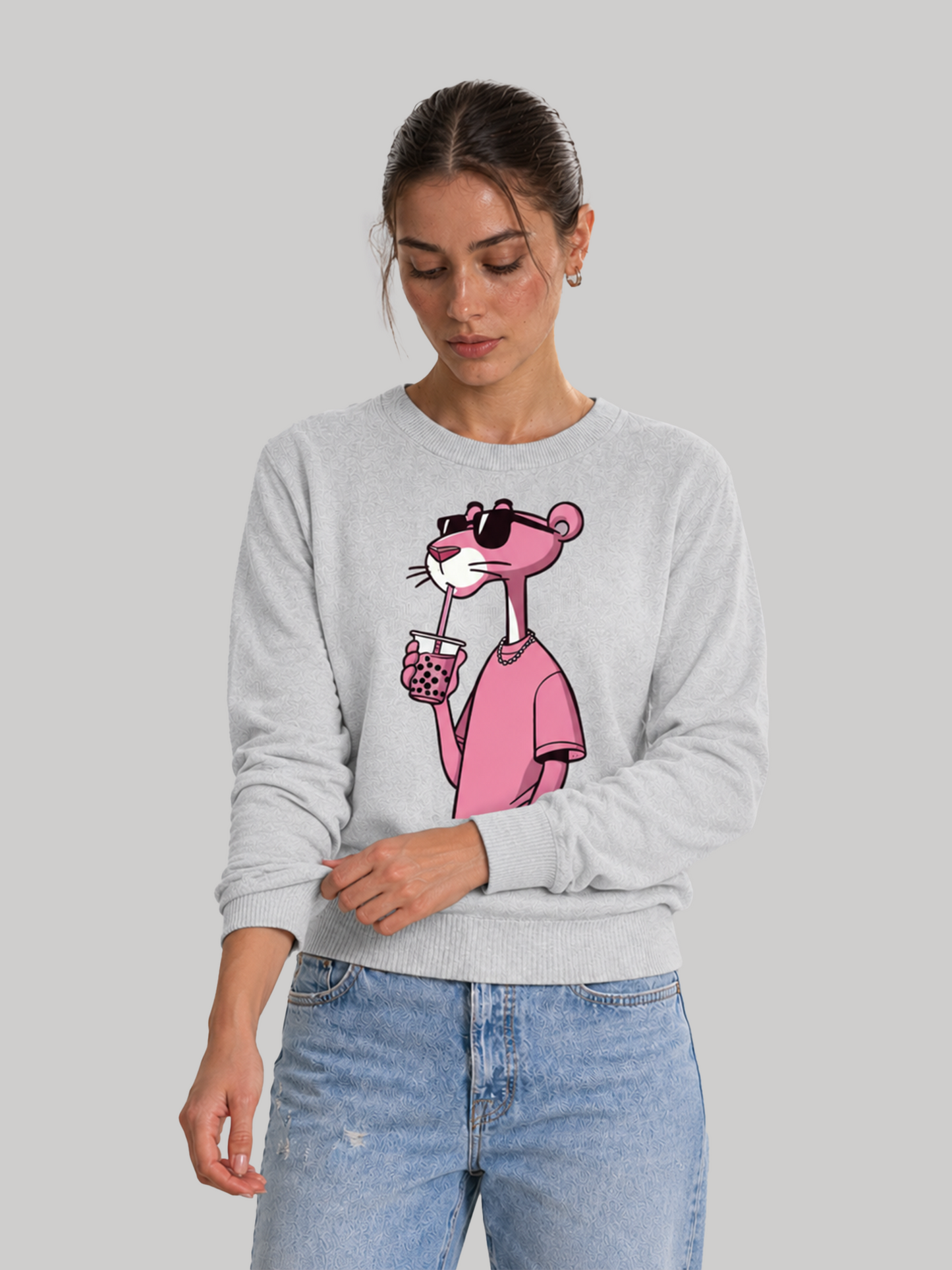 A female model looking down while gently rolling up the sleeve of an melange grey custom graphic printed sweatshirt.