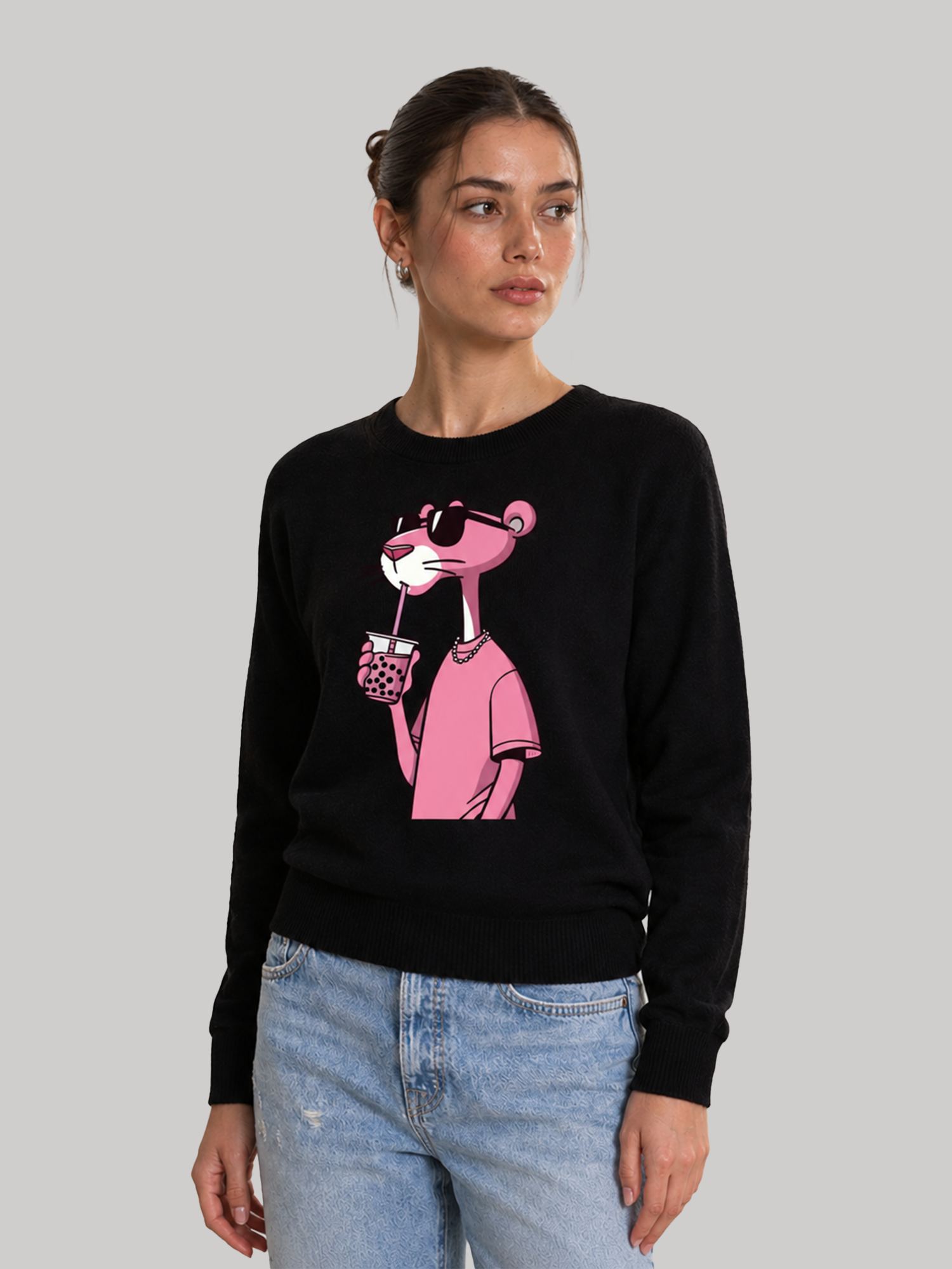 A slight three-quarter view of a female model looking away, showcasing the comfortable shoulder fit of a black sweatshirt with a cartoon character print.