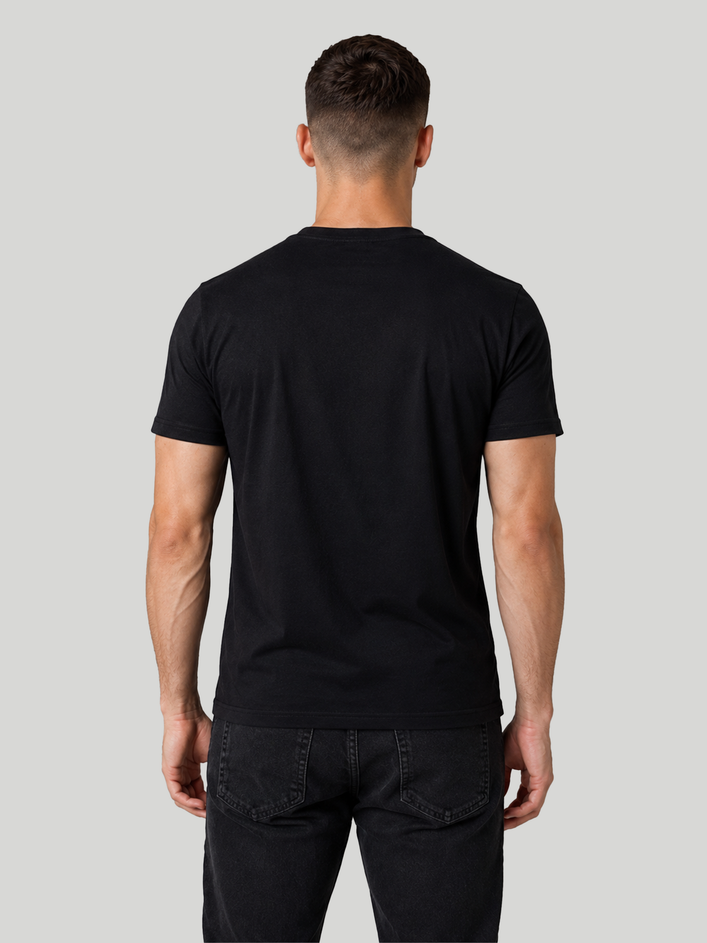 The straight rear view of a male model showcasing a solid black half-sleeve cotton t-shirt, emphasizing its clean fit and shoulder structure.