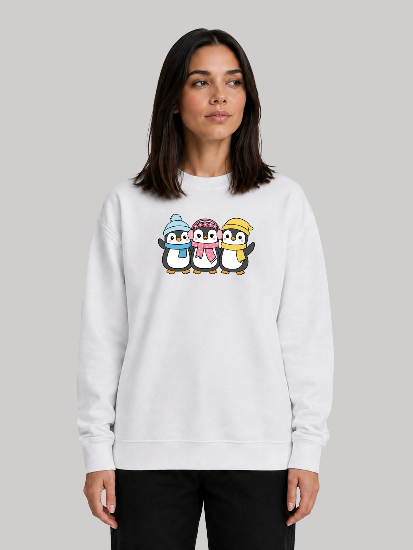 A front studio shot of a female model looking away slightly, showcasing the relaxed and comfy fit of a white sweatshirt with a winter penguin graphic.