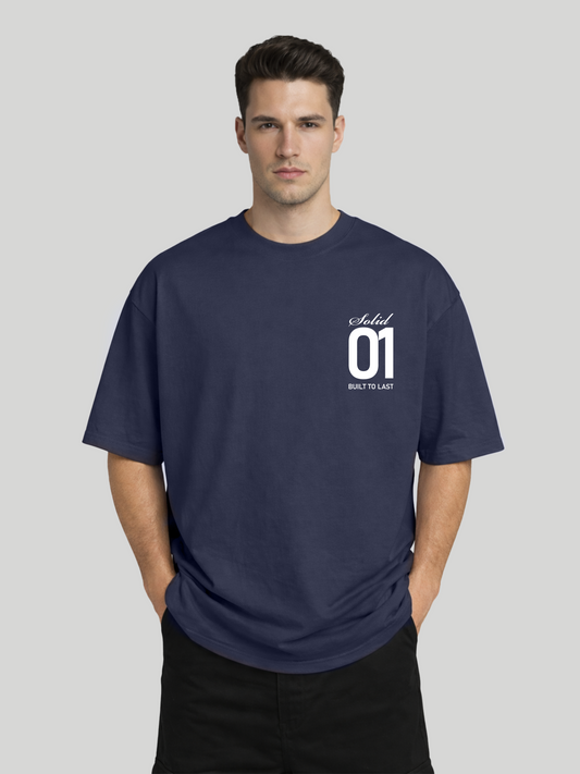 Man wearing midnight blue oversized t-shirt with Solid 01 chest print in relaxed pose with hands in pockets