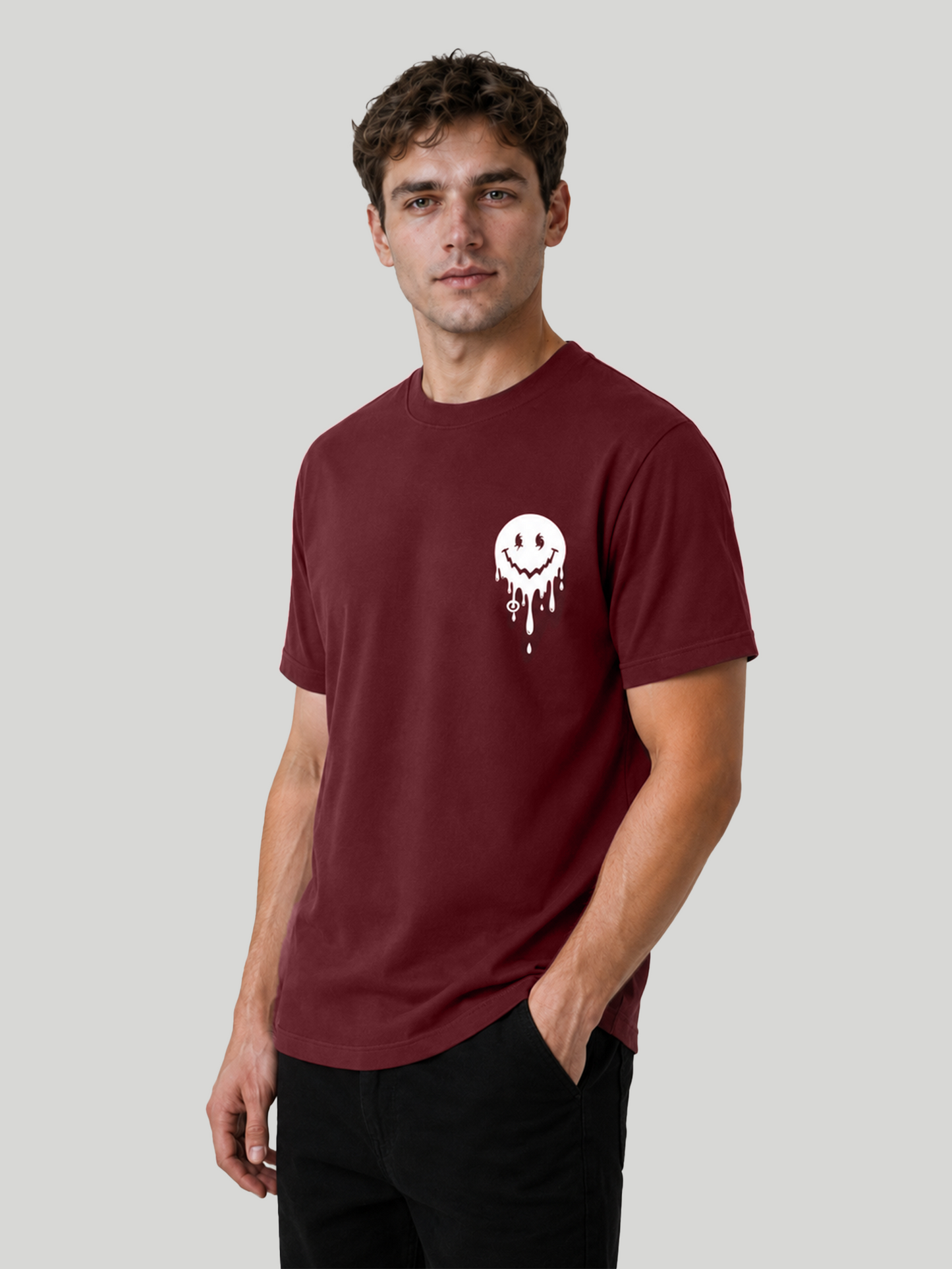 A three-quarter front view of a male model posing with his hand in his pocket, highlighting the fit and sleeve structure of a maroon printed streetwear t-shirt.